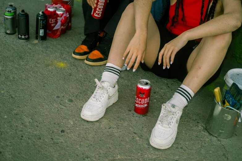 two people sit near a can of soda and two cans of soda