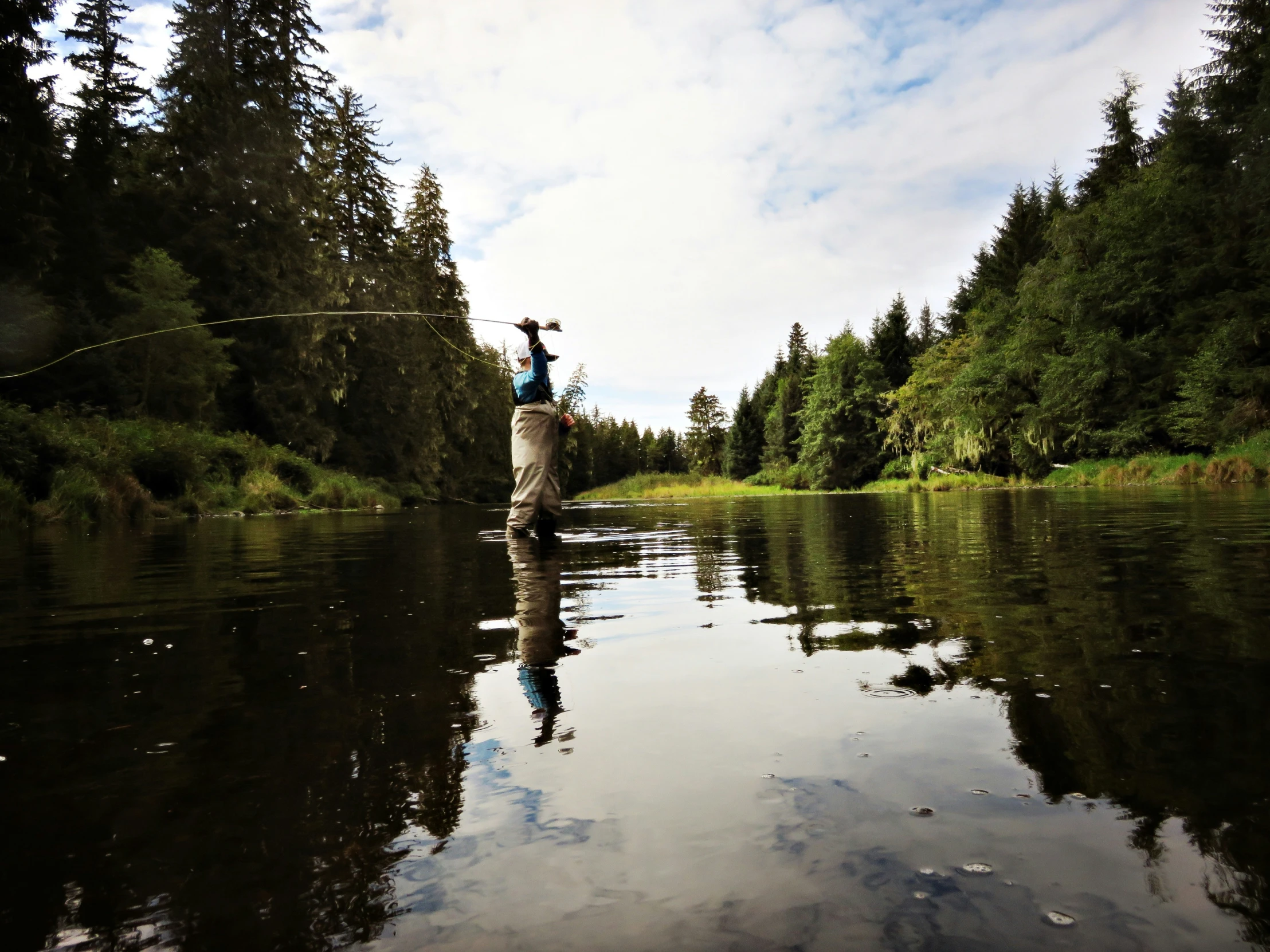 a man fishing on a river in a canoe