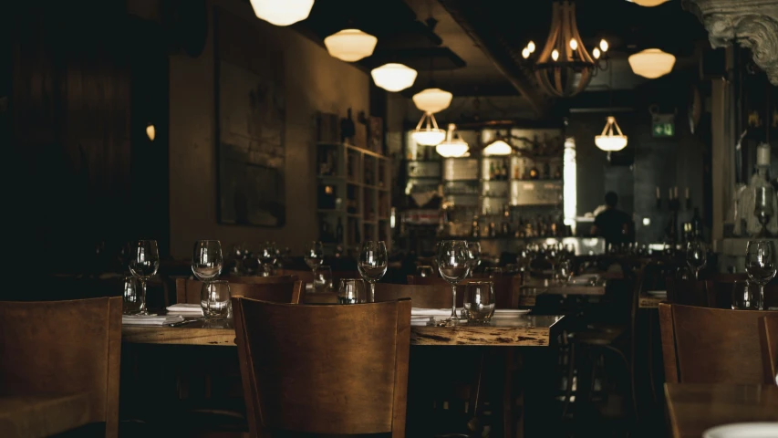 tables and chairs in a bar with wine glasses on it