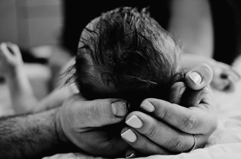 a close up of a person laying in bed with her hand near the baby's head