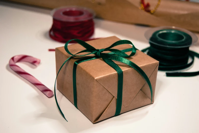 a brown gift box with green ribbon and a christmas candy cane