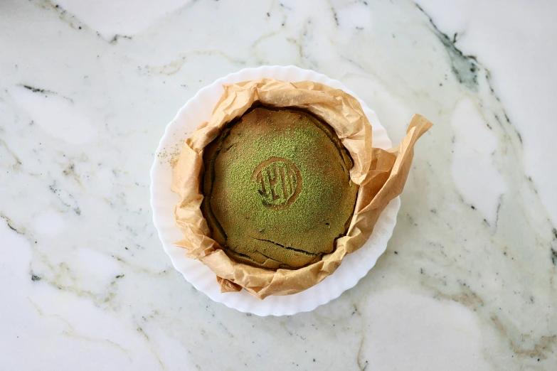 green cake inside of a paper container on top of a marble counter