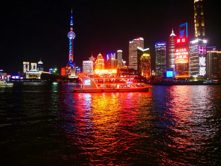 a river boat floats past the brightly lit city lights