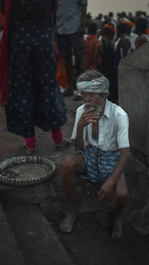 a man sitting on the ground with his feet crossed while talking on his cell phone