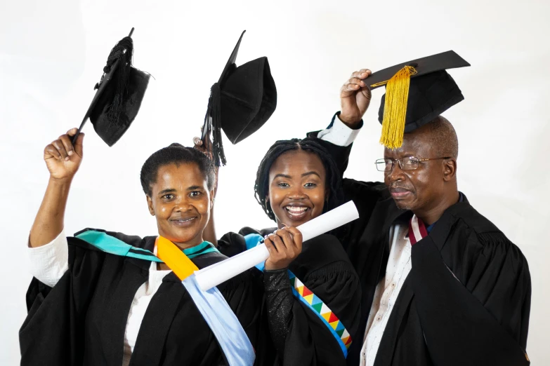 three people hold up their diplomas in preparation for a graduation ceremony