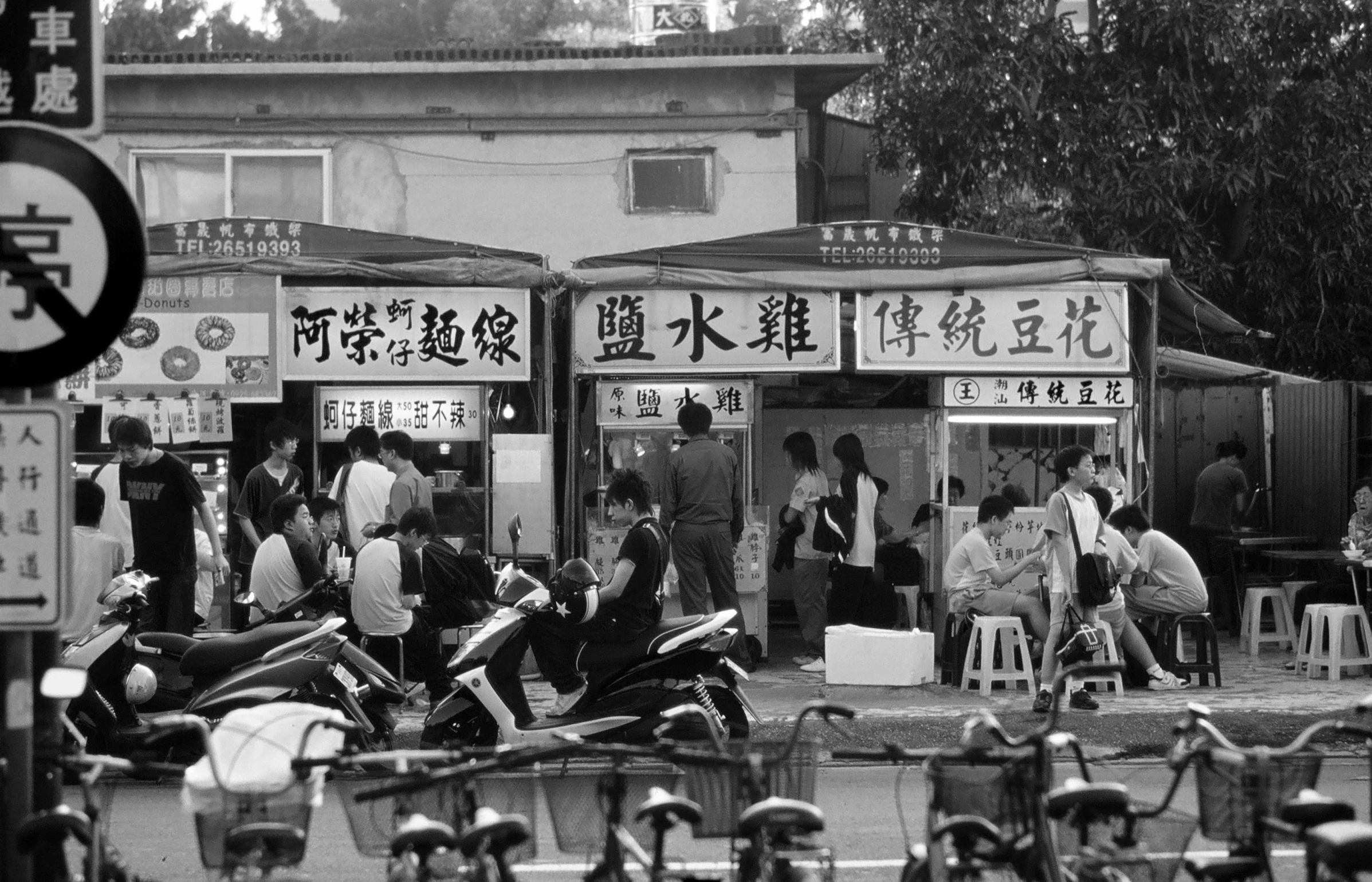 black and white po of people walking by a market