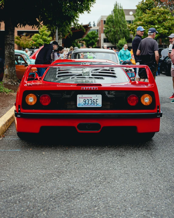 the red car is parked in front of a crowd