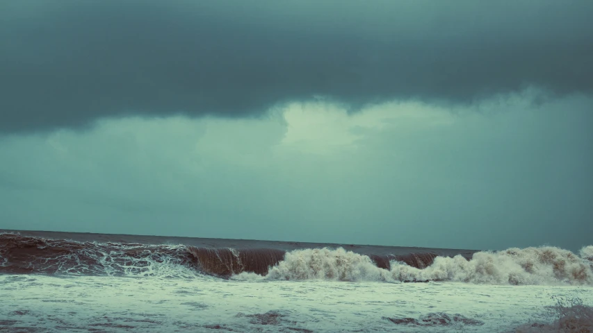 man riding a surf board out in the waves on a stormy day