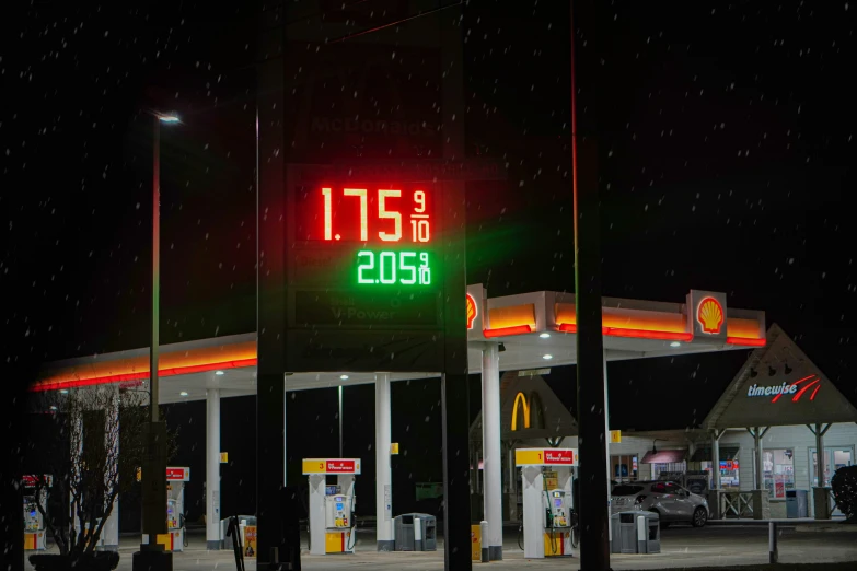a gas station has a neon sign and two gas pumps