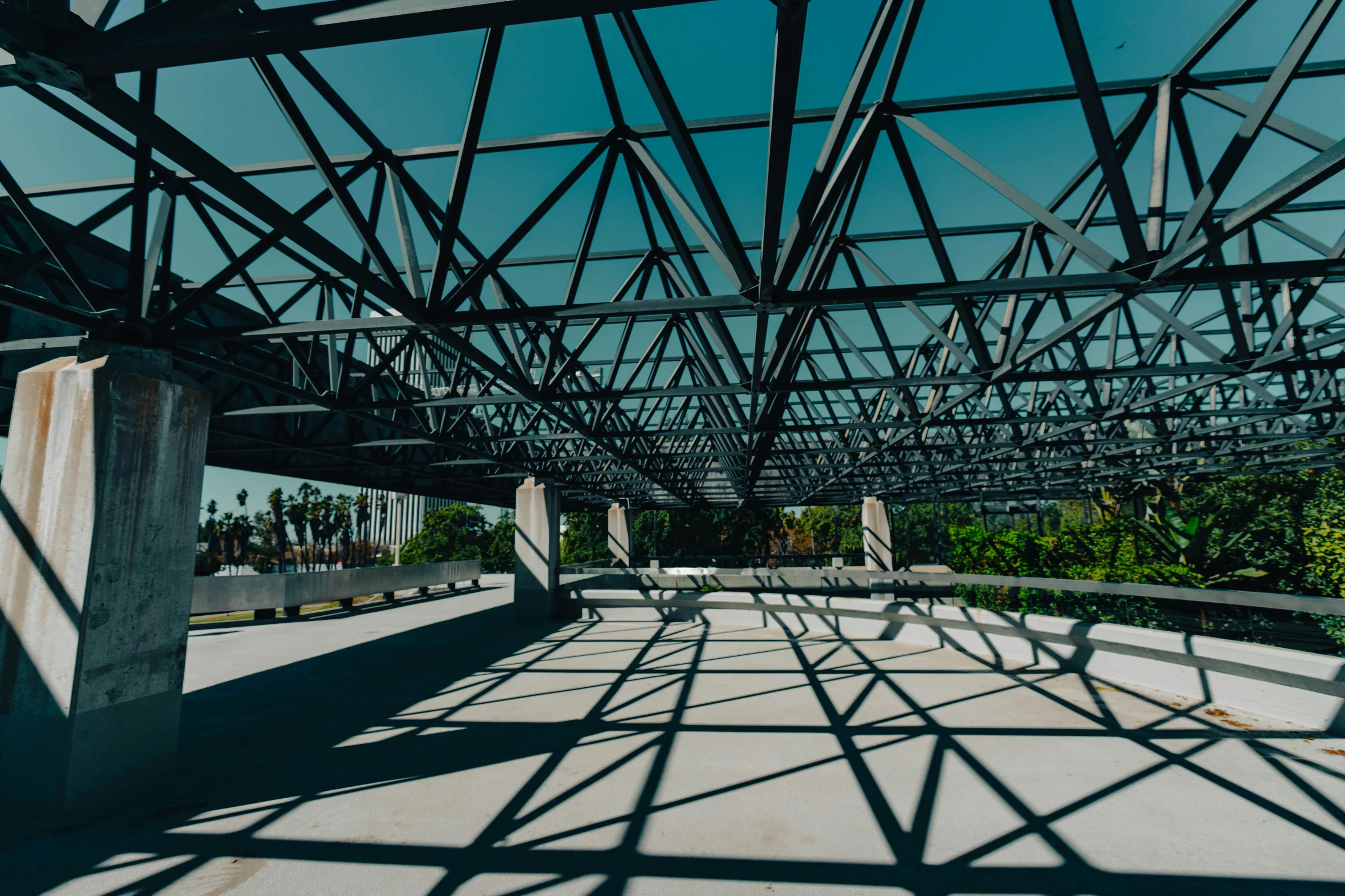 the walkway underneath a bridge with shadows on it