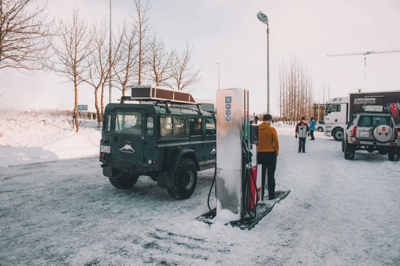 vehicles on a snowy street while people stand near them