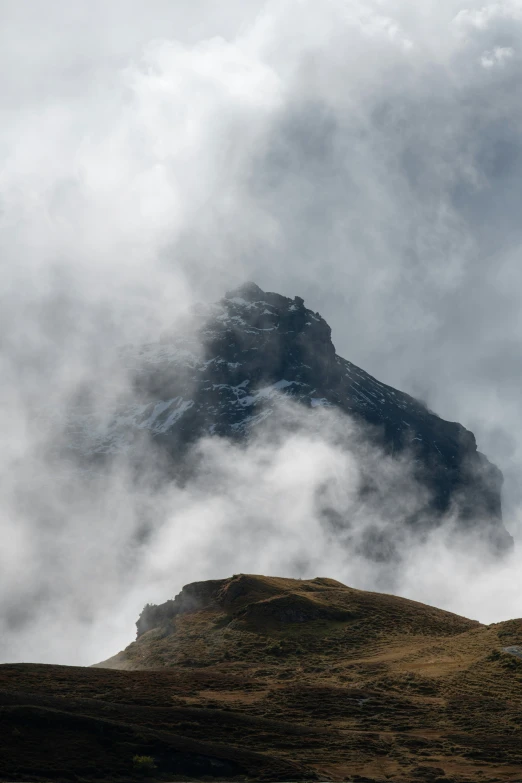 a view from the ground of a rocky outcrop with clouds in the sky