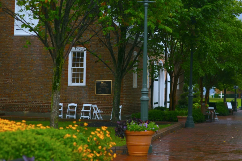 two potted flowers near an orange planter with chairs in front of it