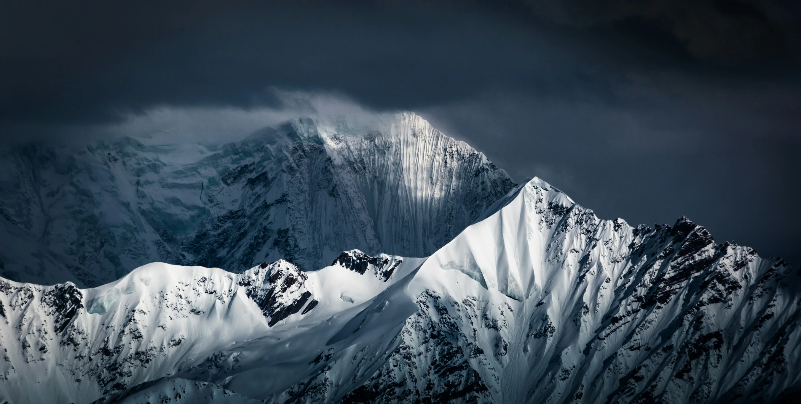 a snowy mountain covered in white snow under a cloudy sky