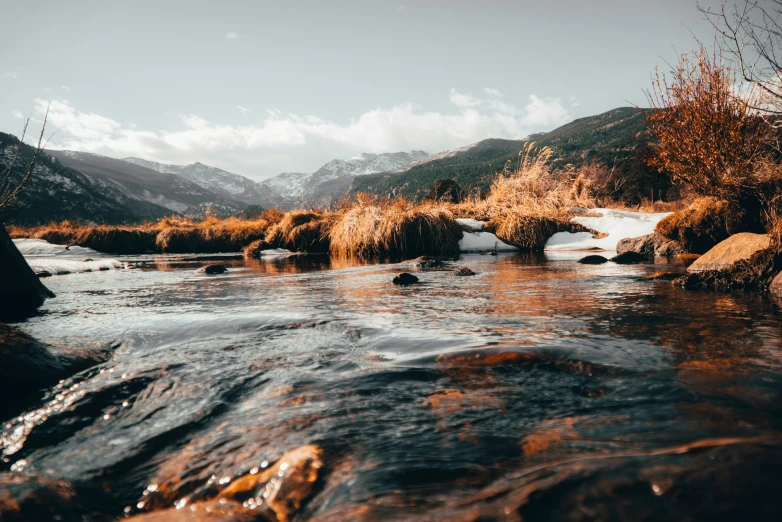 water flowing through a river next to some mountains