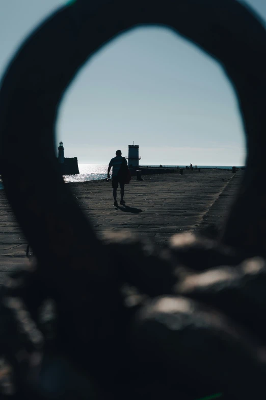 a man walking along a pier in front of the water