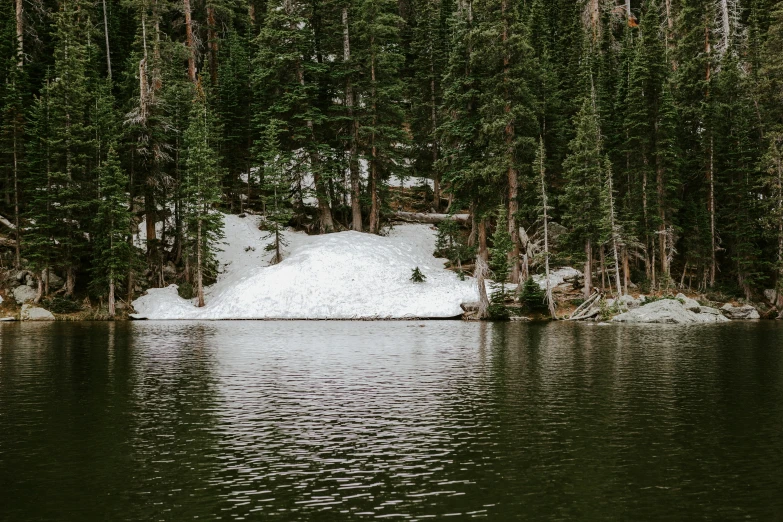 snow is piled up on the bank of a lake