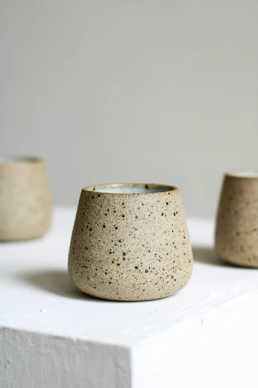 three white and brown vases sit on a white surface