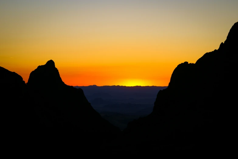 a yellow and orange sky above a mountain range