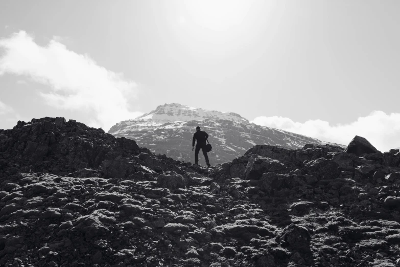 man on top of rock hill under a cloud filled sky