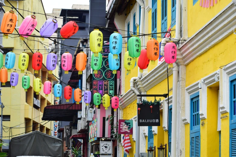 chinese lanterns hanging on wires in front of yellow buildings