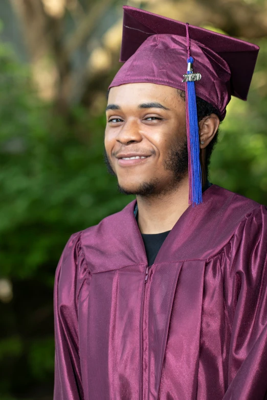 a graduate smiles while wearing his cap and gown