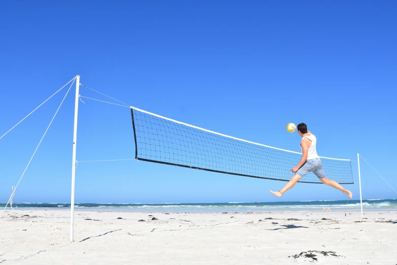 a man running towards a volleyball net on the beach