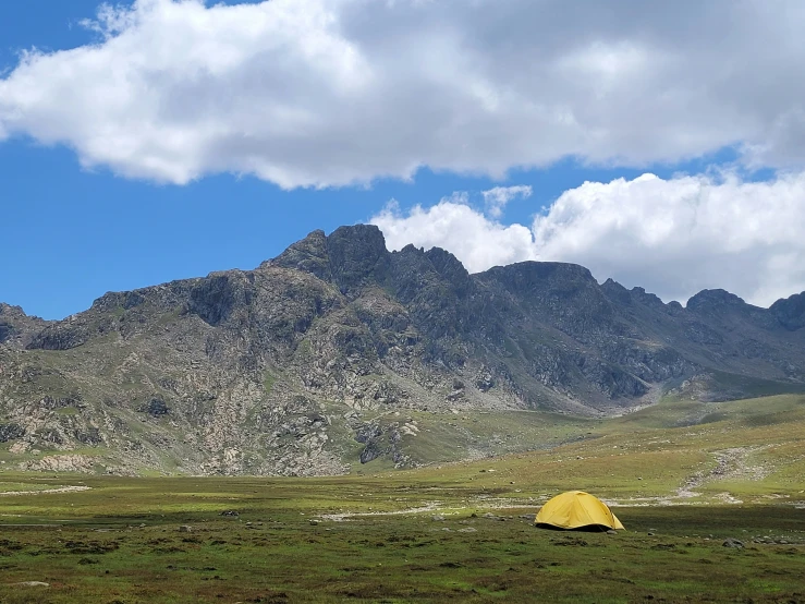 a tent and some mountains under a cloudy sky