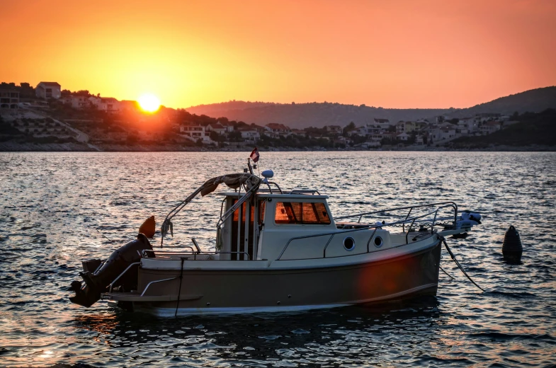 a boat on the water at sunset with city in background