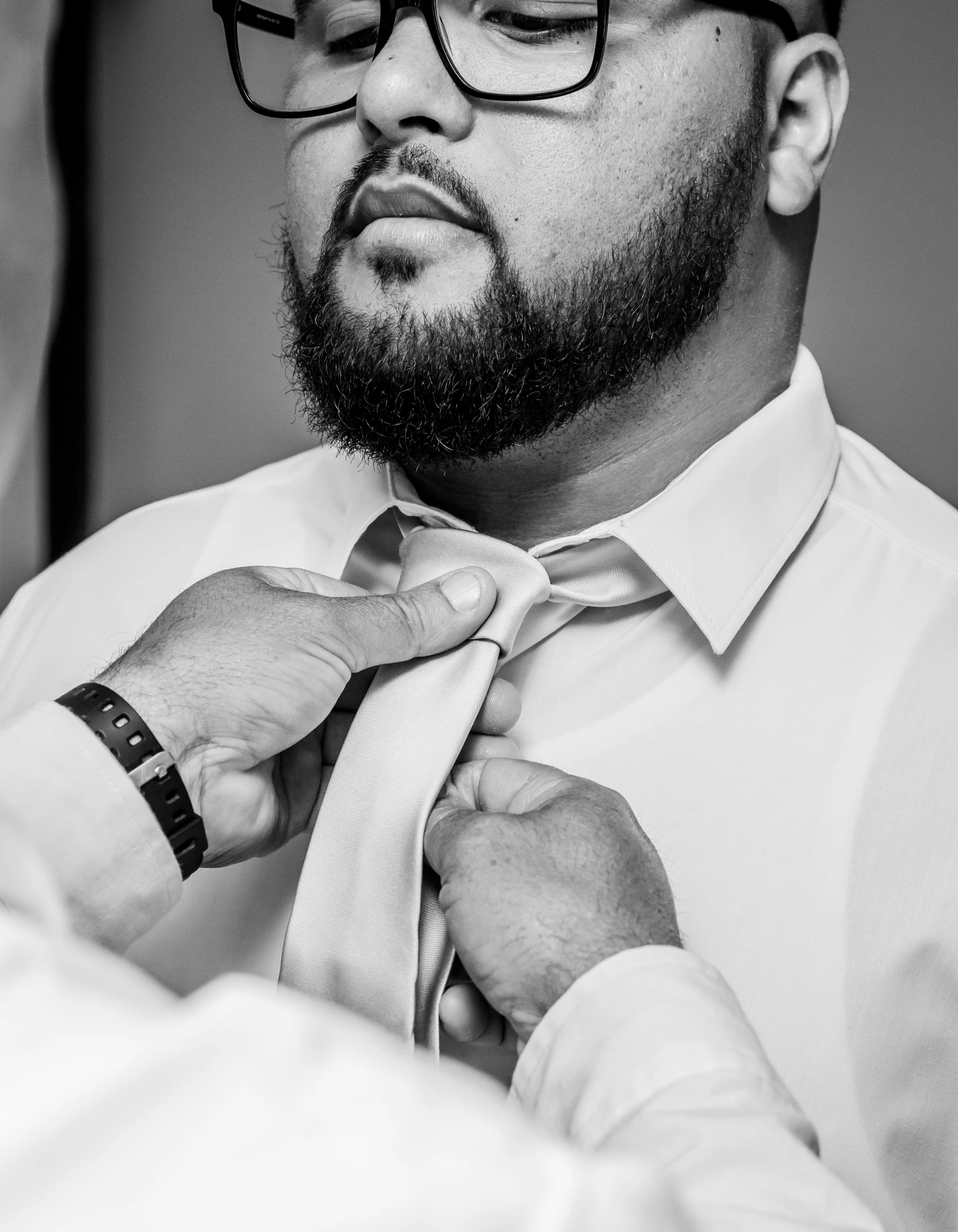 a man is fixing his tie with one hand and looking in the other direction