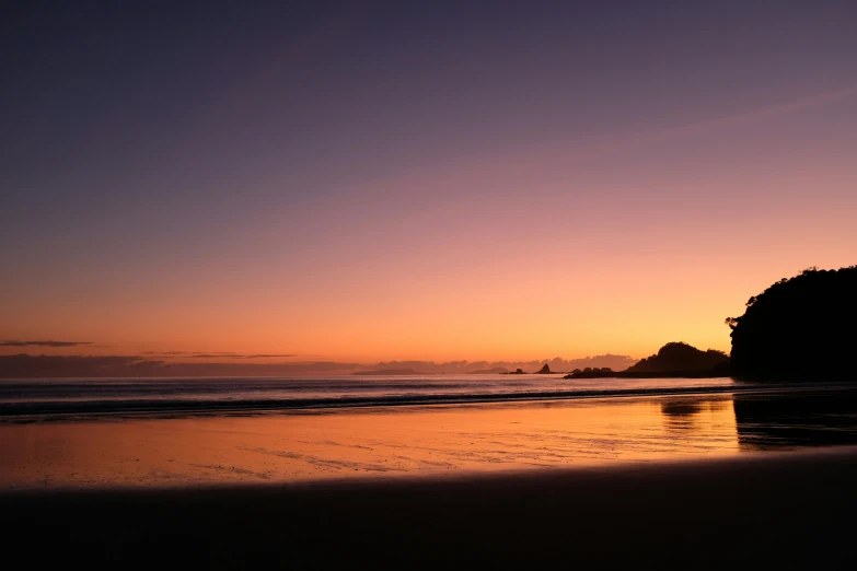 a lone person sitting on the beach with his surfboard