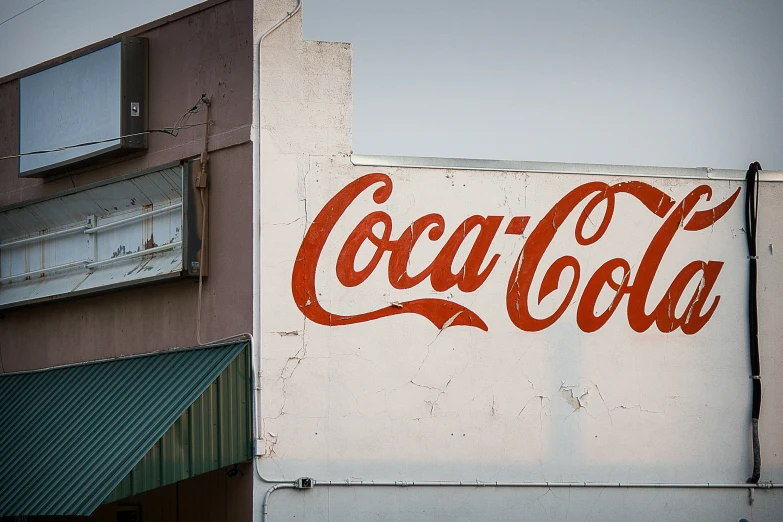 this coca cola sign is outside near a building