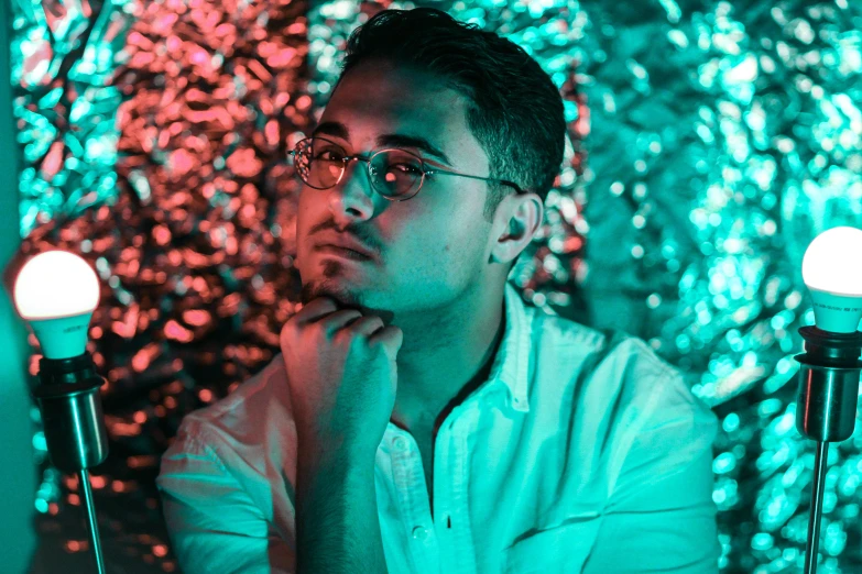 a man in glasses sitting by two candles