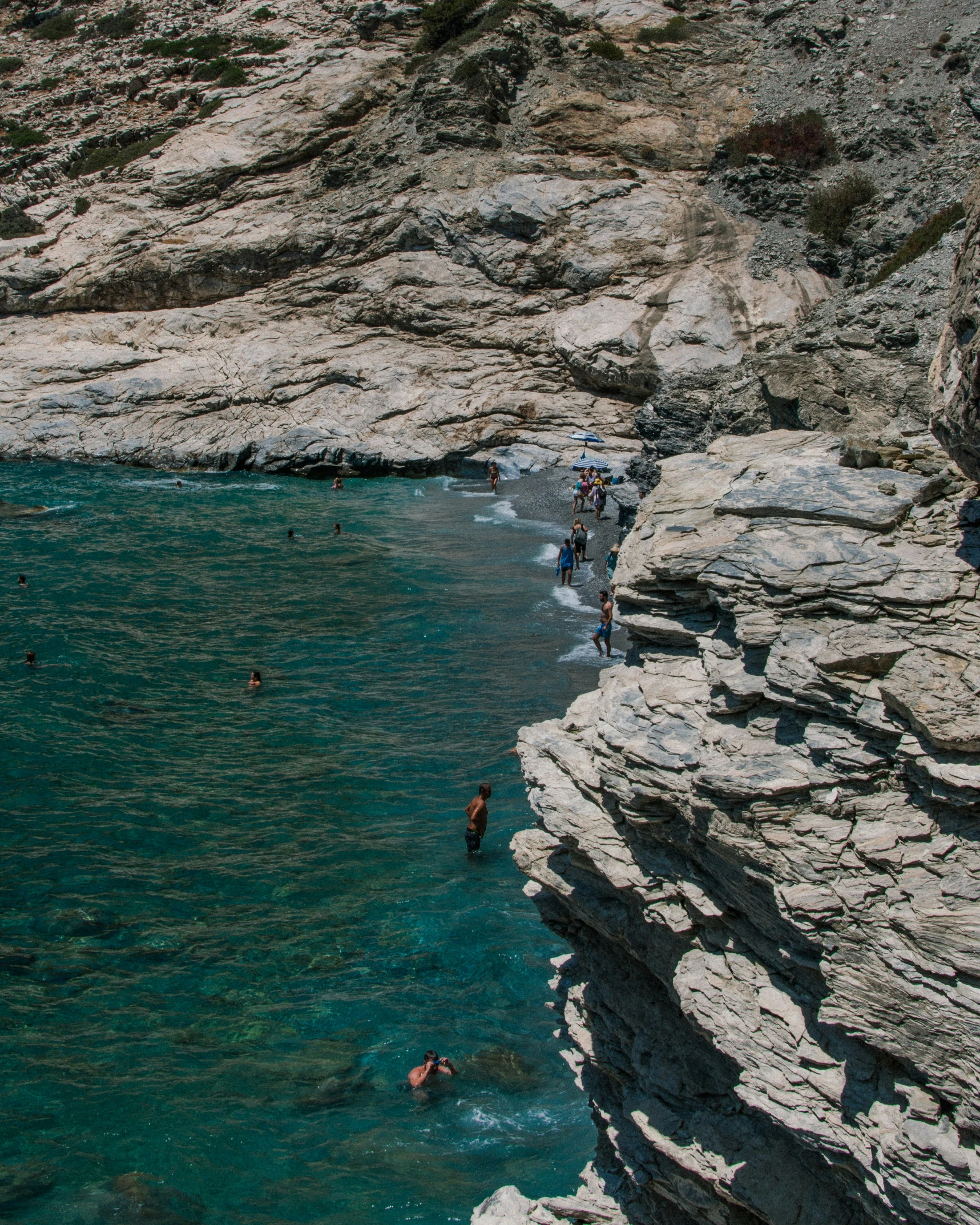 many people swimming in a lagoon on some rocky cliffs