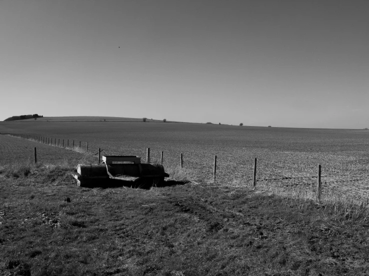 truck parked by a fence in the middle of a grassy field