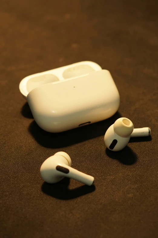 an apple device is laying on the floor next to earbuds