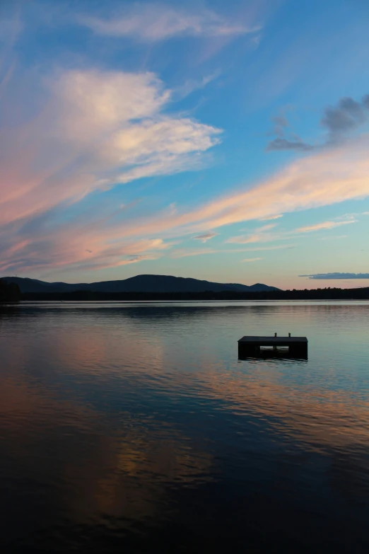 an empty floating dock on a lake at sunset