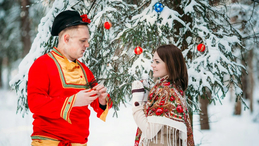 two people standing in front of a snow covered tree