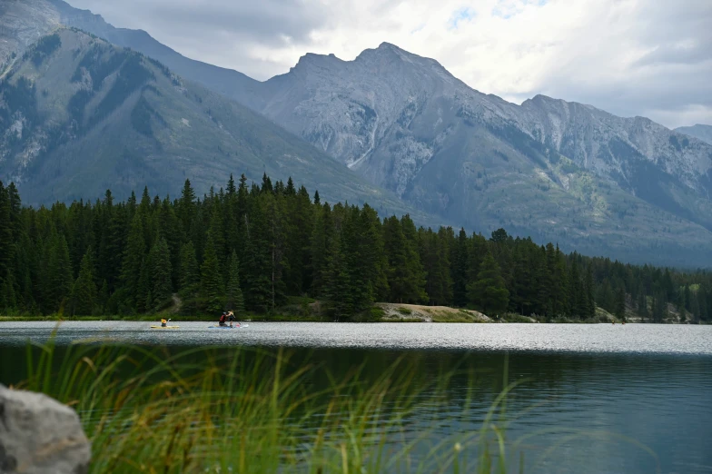 people are in a row boat on a mountain lake