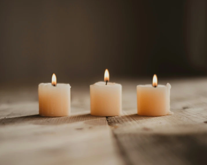 three lit candles on a wooden surface