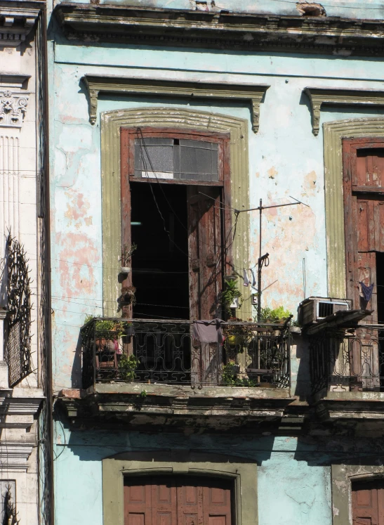 an old building with two balconies and a balcony with plants in the window sill