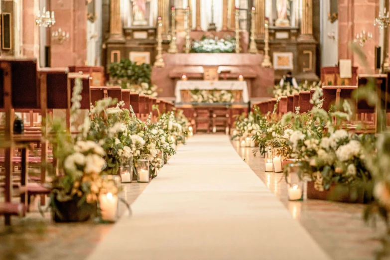 the aisle lined with candles and flowers at an alter