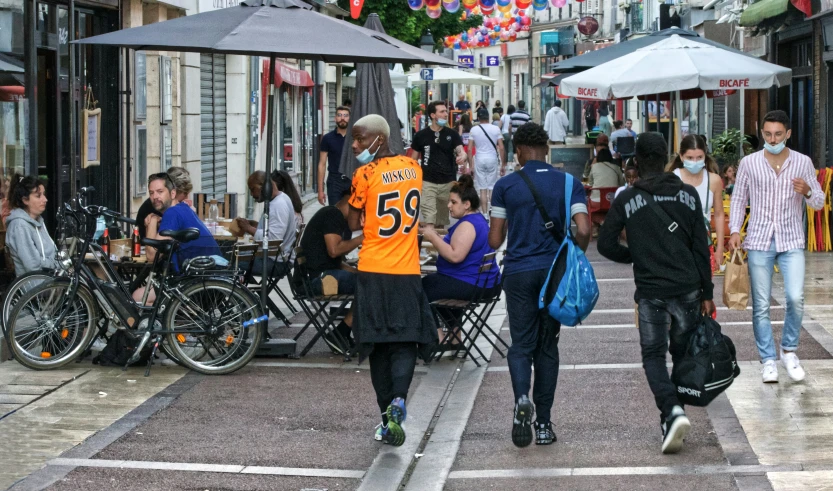 people walking on the street near tables and parked bicycles