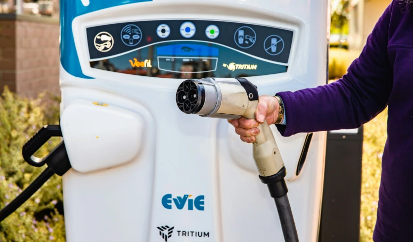 a woman using a gas pump with the help of an electrician