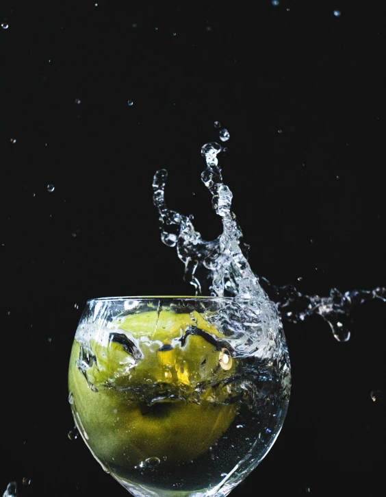 an apple splashing into a glass of water