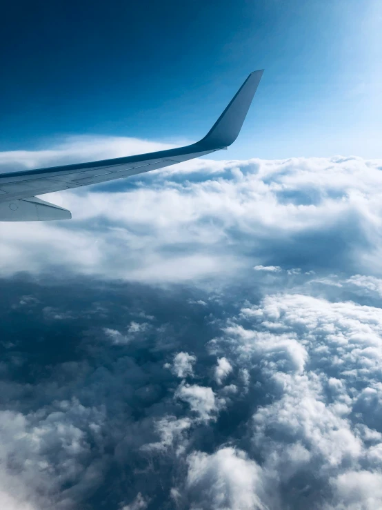 an aerial view of clouds, a plane wing, and the sky