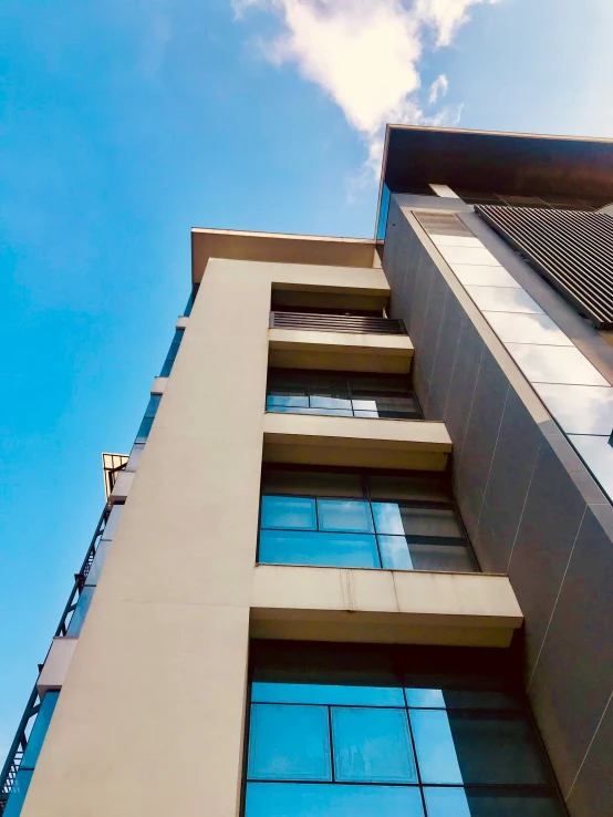 a very tall, modern apartment building with a blue sky background