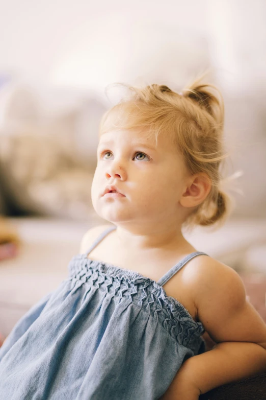 a child with blue dress looks into the distance