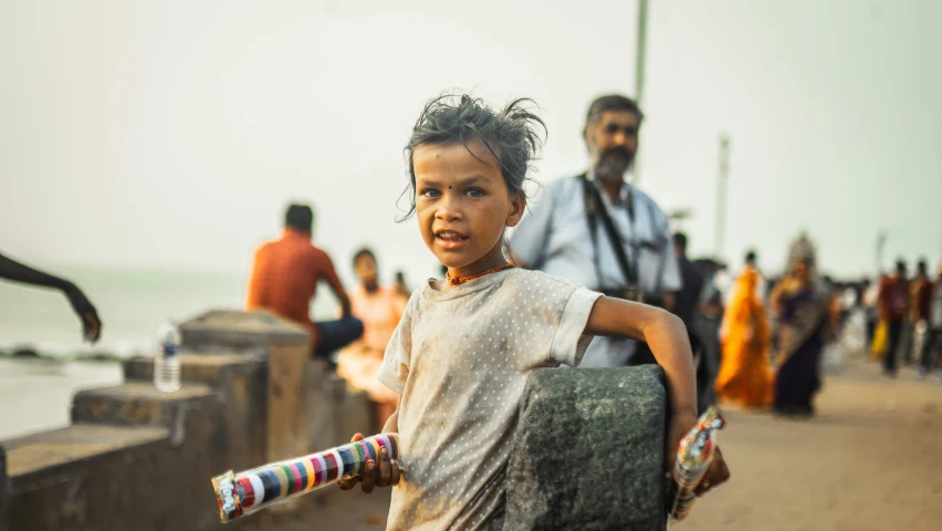 a little boy holding a bat near the beach