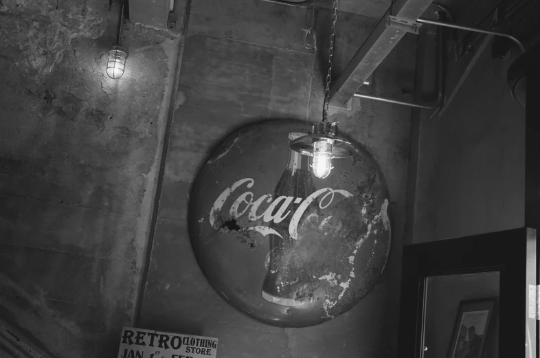 there is a hanging light shade on the ceiling above the soda sign
